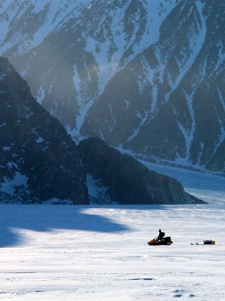 Canadian researcher makes his way along the Belcher Glacier while installing instrumentation to measure the glaciers velocity, Devon Island, Nunavut, Canada. This helps the researches determine how much ice is being transported from the interior of the De