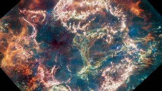 A wall of green was blooms at the center of a colorful supernova remnant