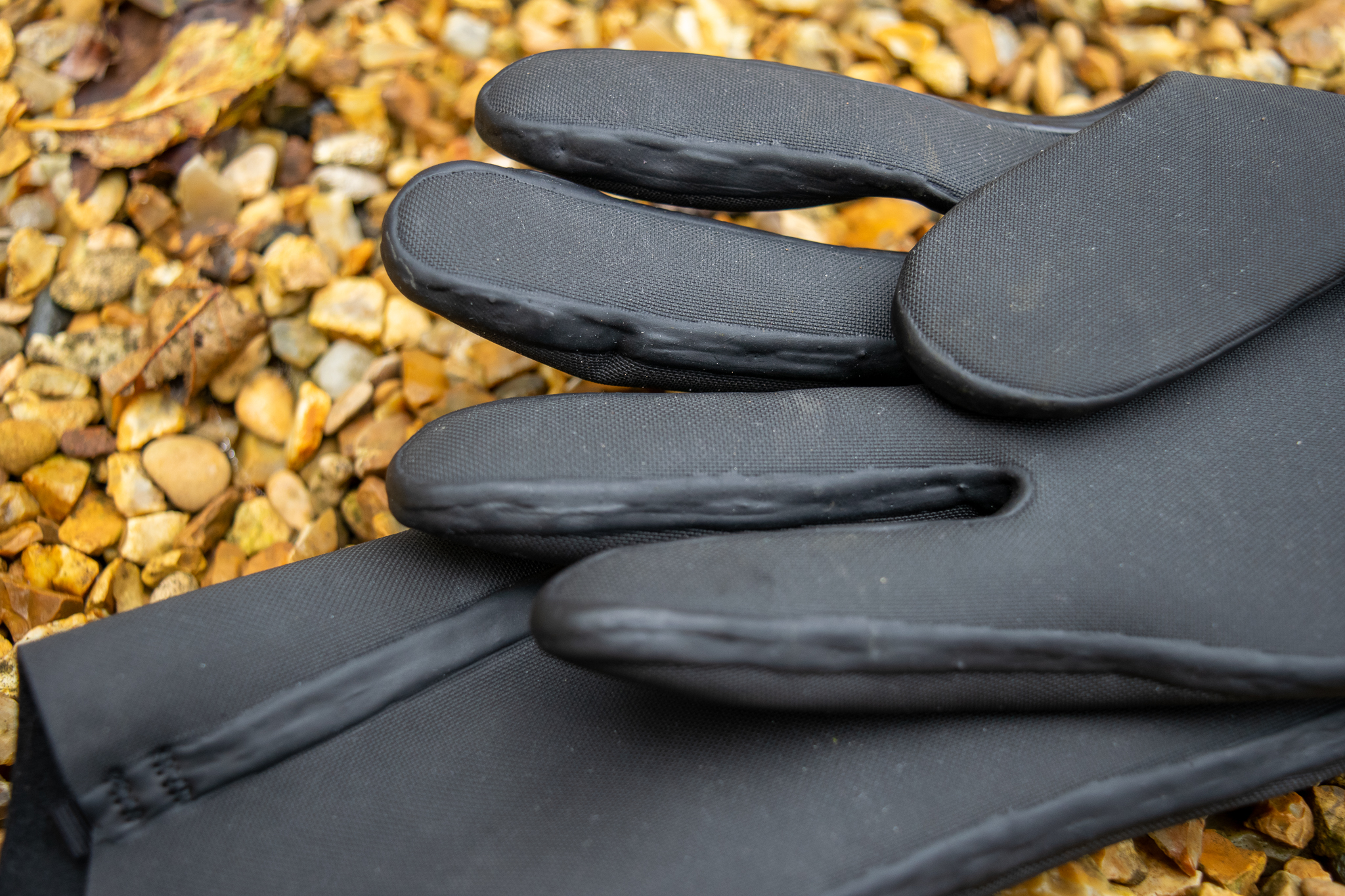 Velotoze neoprene gloves on some gravel with water droplets on them