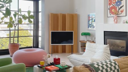 a living room with a colorful donut pouf a togo chair and a bamboo divider