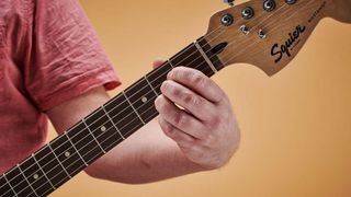 Close-up of a man's hand playing an A chord on an electric guitar