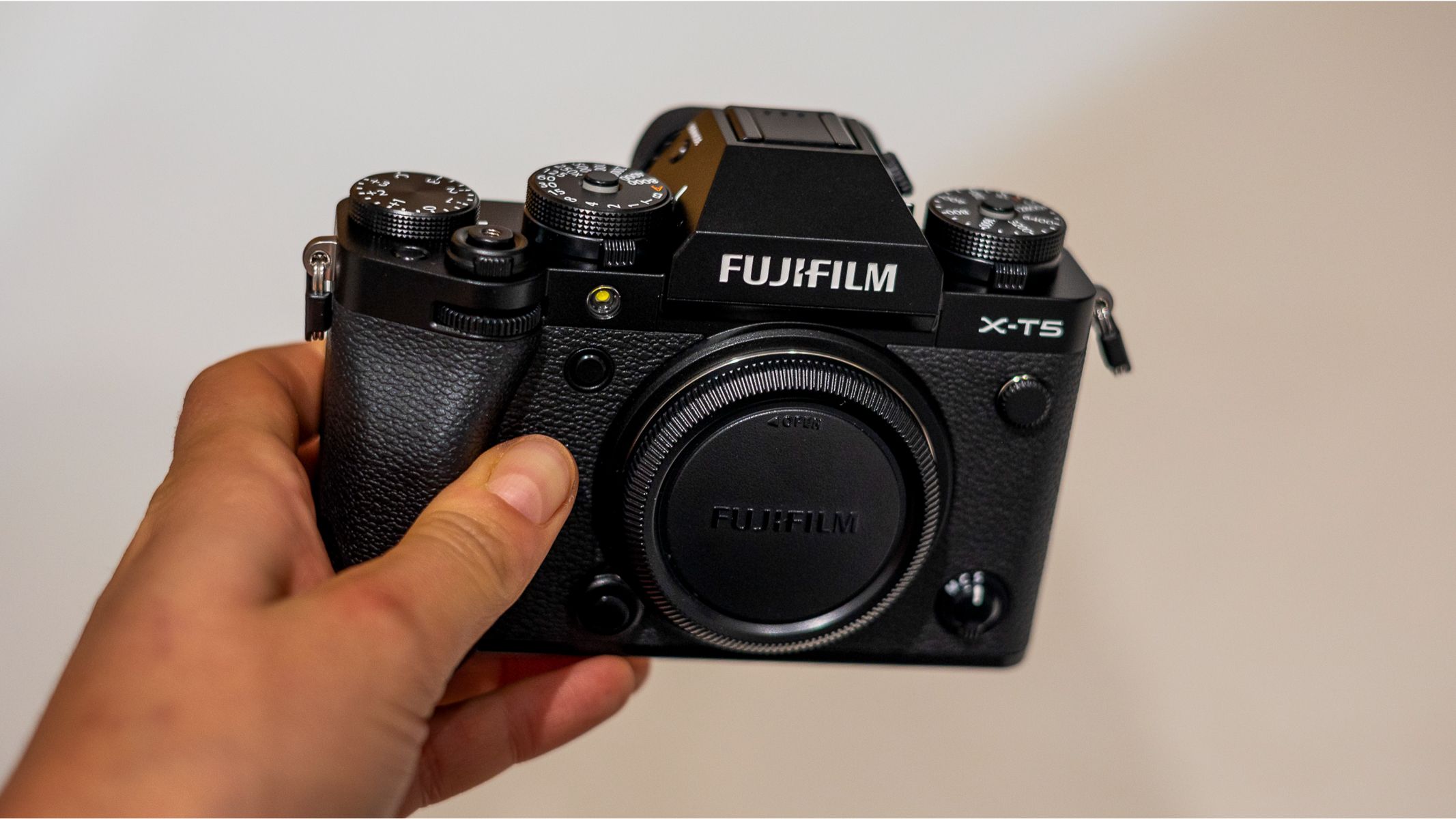Fujifilm X-T5 in-hand against a white background
