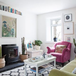 bright white living room with pink armchair, books and houseplants