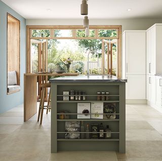 green kitchen island, white cabinets and wooden window frame