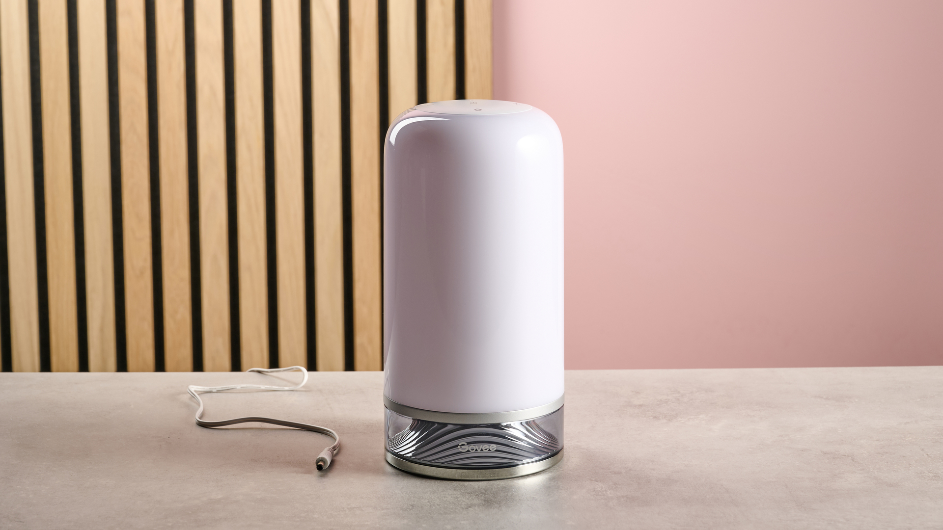 The Govee Table Lamp 2 is unlit and sits on a stone surface with wooden slats and a pink wall behind.