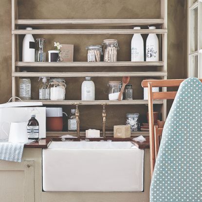 A sink with a shelf of cleaning products and an ironing board