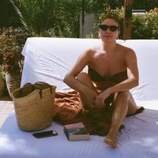 Emma Hoareau at the pool, wearing a bikini, towel and raffia basket bag.