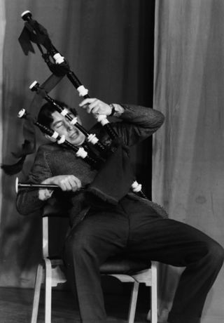 Prince Charles, the Prince of Wales, joking around with a set of bagpipes as he appears on stage in a student revue in 'Quiet Flows the Don', at Trinity College, Cambridge University, February 23rd 1970.