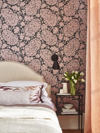 bedroom with blush wallpaper, coral drapes, neutral bed, black side table and wall light