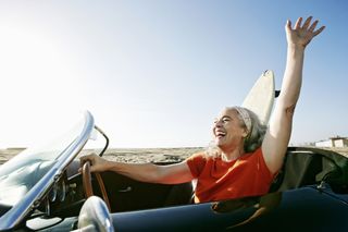 A woman drives a car next to a beach