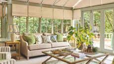 Sunroom with light green walls, rattan shades and pale beige sofa