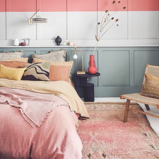 bedroom flooring ideas, pink and yellow bedding, grey panels with pink stripe, pink vintage rug, wood chair