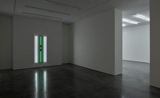 Empty room with white and green lighting tubes on wall and ceiling