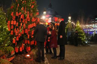 Prince George, Princess Charlotte, Prince Louis, Kate Middleton and Prince William looking at a Christmas tree covered in red tags outside Westminster Abbey