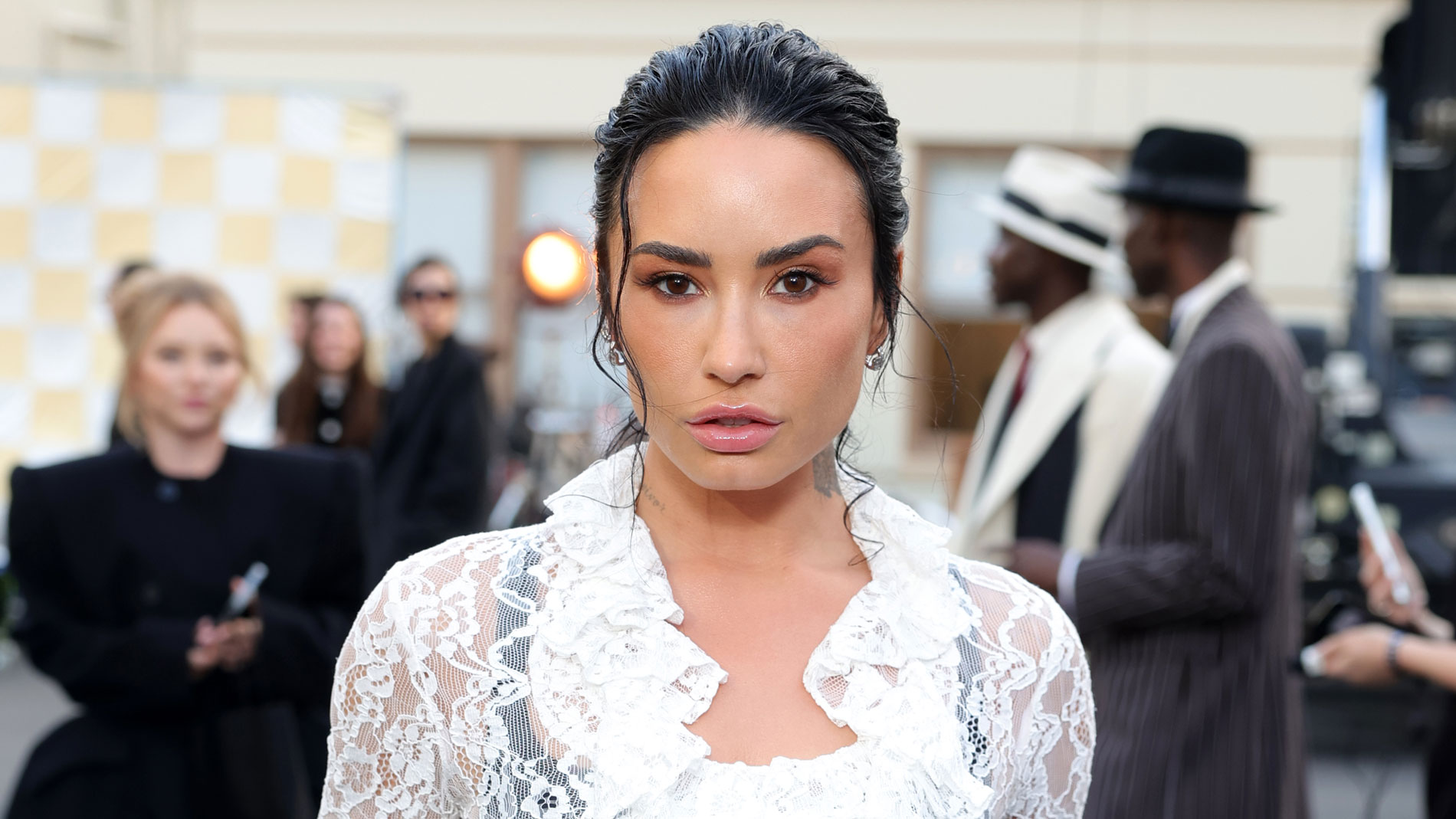 Demi Lovato wears a white lace skirt with black tights.