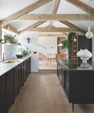 kitchen with minimalist black cabinetry and white worktops and exposed beams and white walls