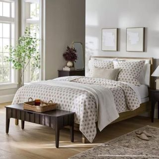 A bedroom with patterned bedding, a green bedframe, and a dark wooden bench at the end of the bed