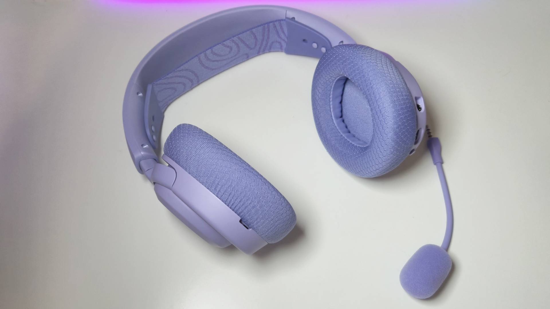 Photos of the SteelSeries Arctis Nova 3 Wireless gaming headset in Lavender, taken by writer Rosalie Newcombe, on a white desk.