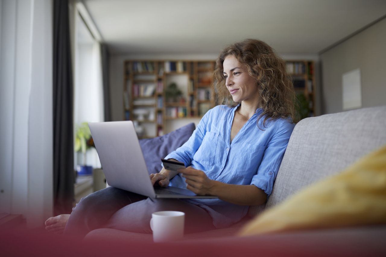 Budgeting apps: Smiling woman doing online shopping on laptop at home