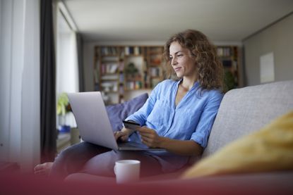Budgeting apps: Smiling woman doing online shopping on laptop at home