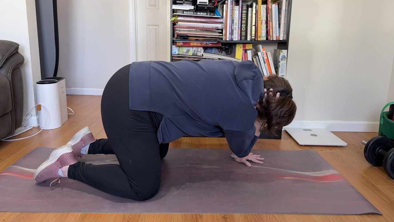 Jennifer Rizzuto performs a thoracic stretch. She is balancing on her knees and her left hand while her right hand is behind her head. Her elbow is pointing down.