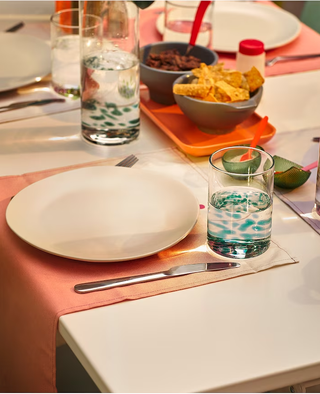 An outdoor table laid with plates, glasses and cutlery