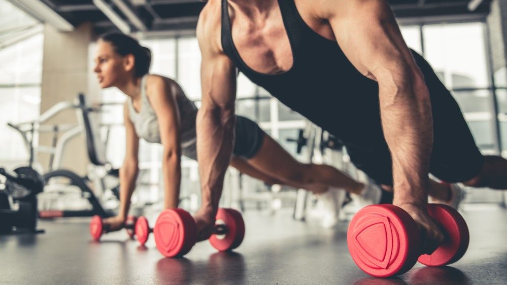 a couple using dumbbells in the gym