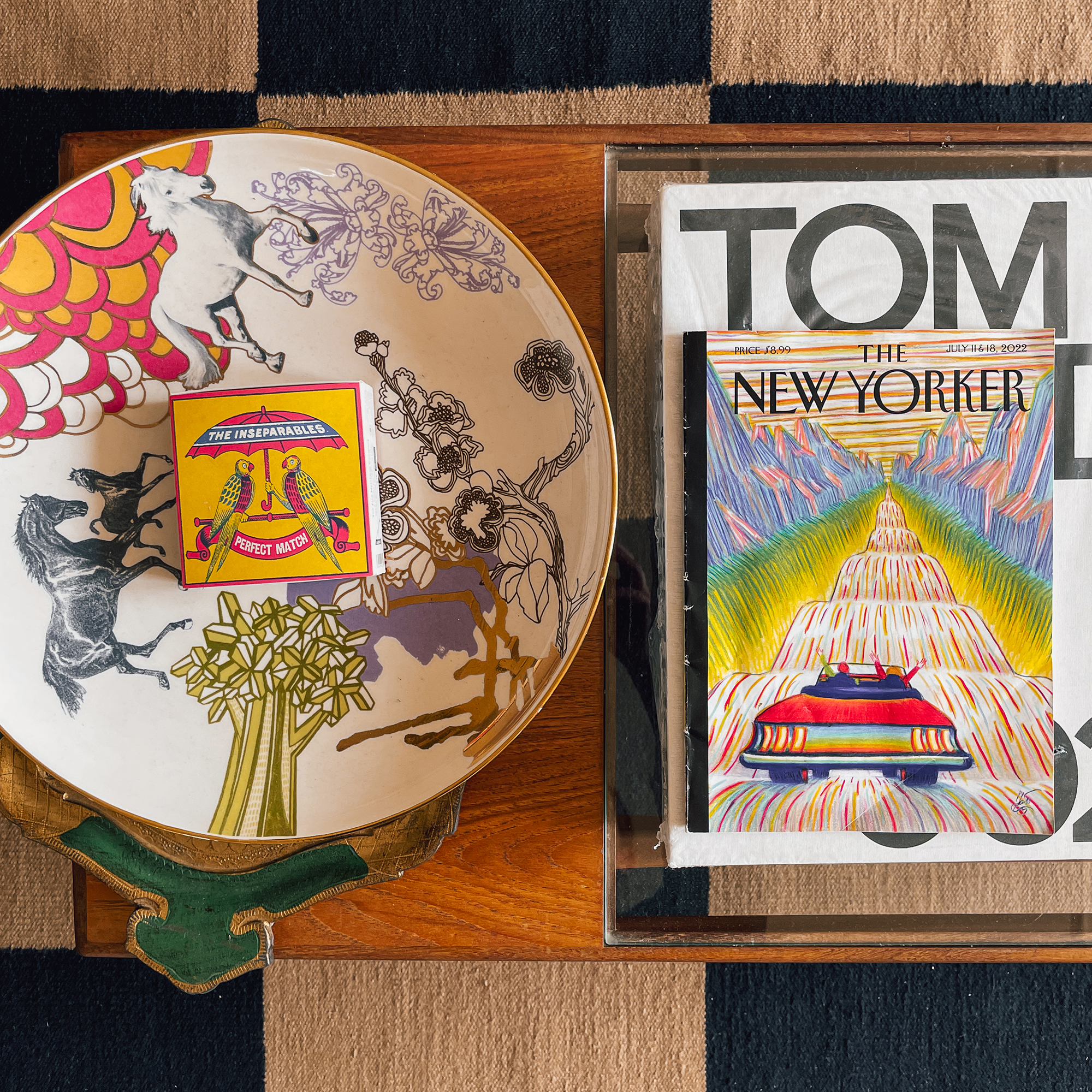 Overhead detail of a wooden coffee table styled with a bowl and a stack of coffee table books and magazines