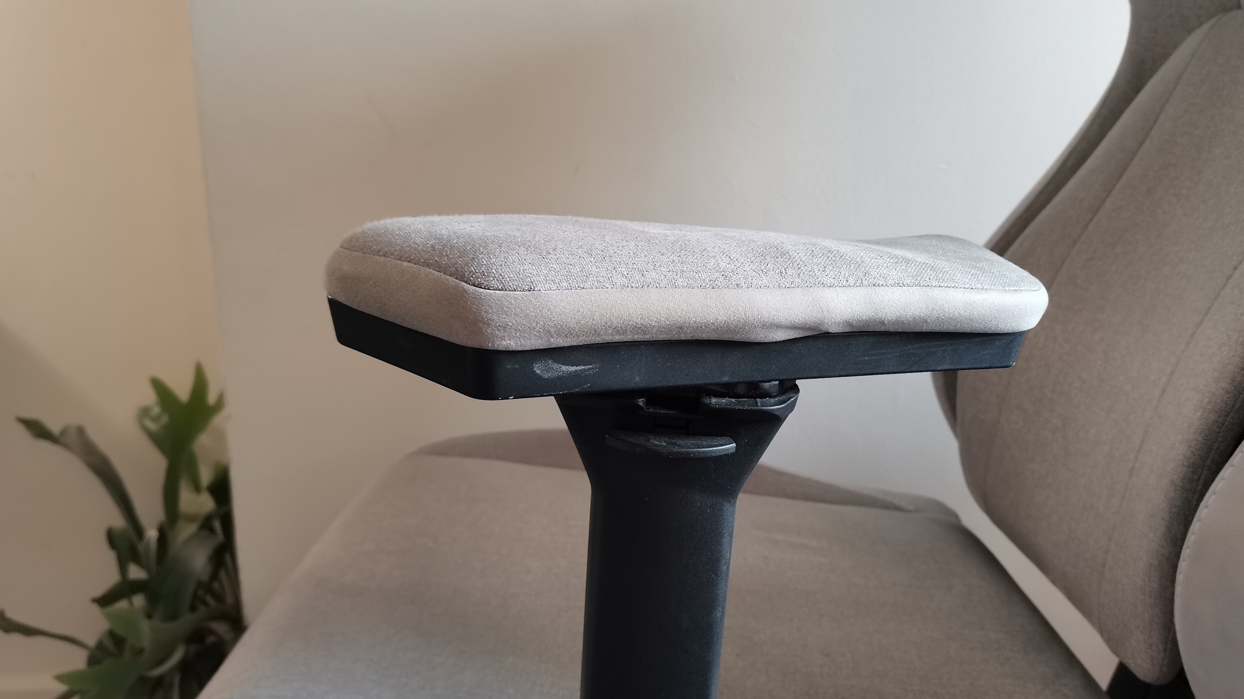 The ThundercoreX3 Core gaming chair in grey in front of a pale wall, next to a wooden bed frame