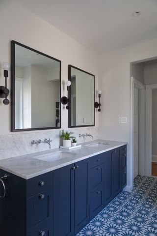 navy blue bathroom with blue units, double mirror and patterned floor tiles