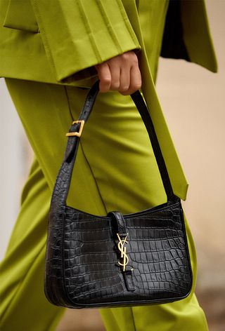 a close-up photo of a woman carrying a black Saint Laurent crescent bag