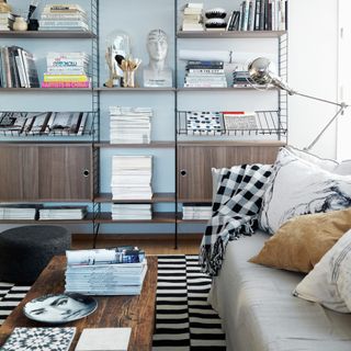 A living room with a geometric black and white rug and a chequered throw on a light grey sofa