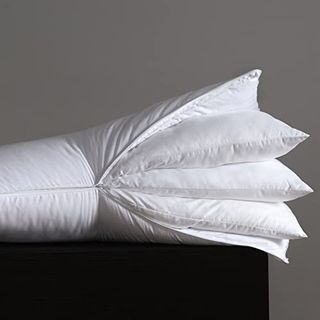 A whtite pillow, partially unxipped cover showing three pillow inserts inside