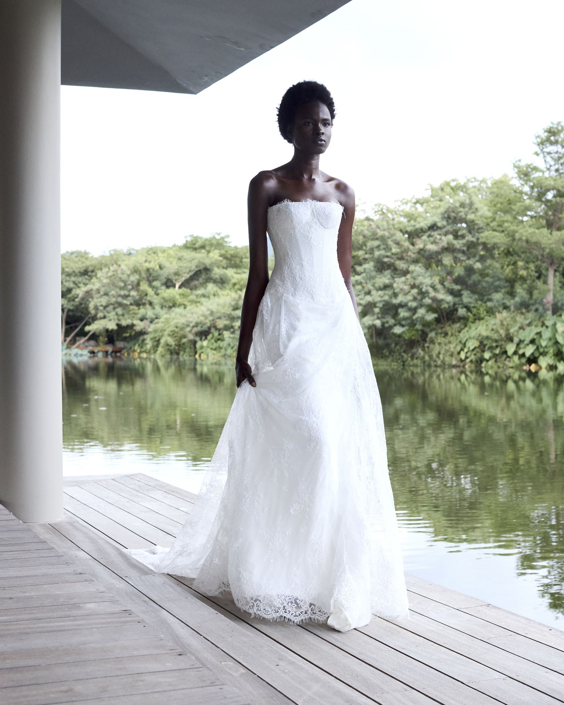 A woman wears a strapless lace gown.