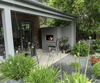 A covered patio area next to a house with an outdoor fireplace and outdoor seating all protected from the weather