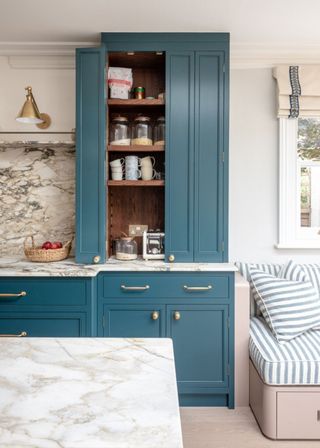 A large blue kitchen cabinet with a bench on the right with storage at the bottom.