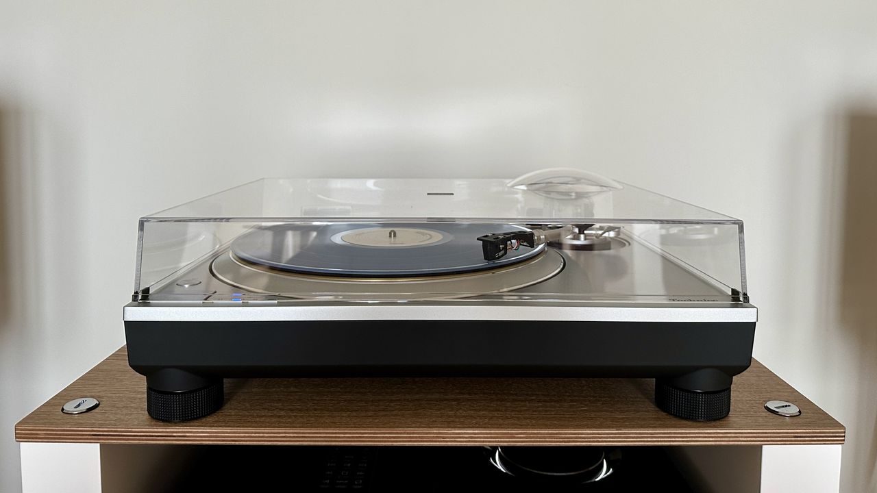 Technics SL-1300G turntable, with the dust cover closed, on a wooden platform.