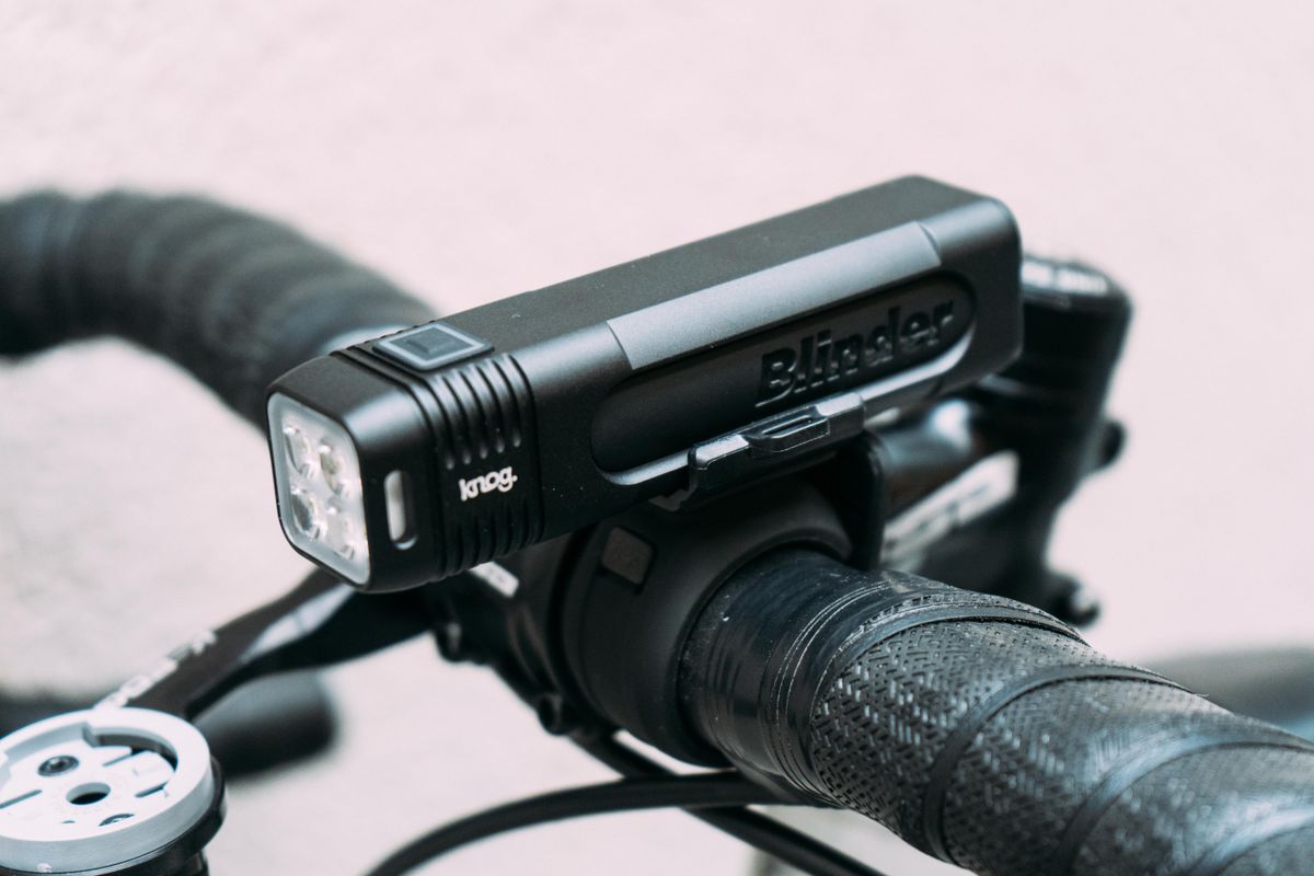 A black bike light mounted on top of a set of handlebars