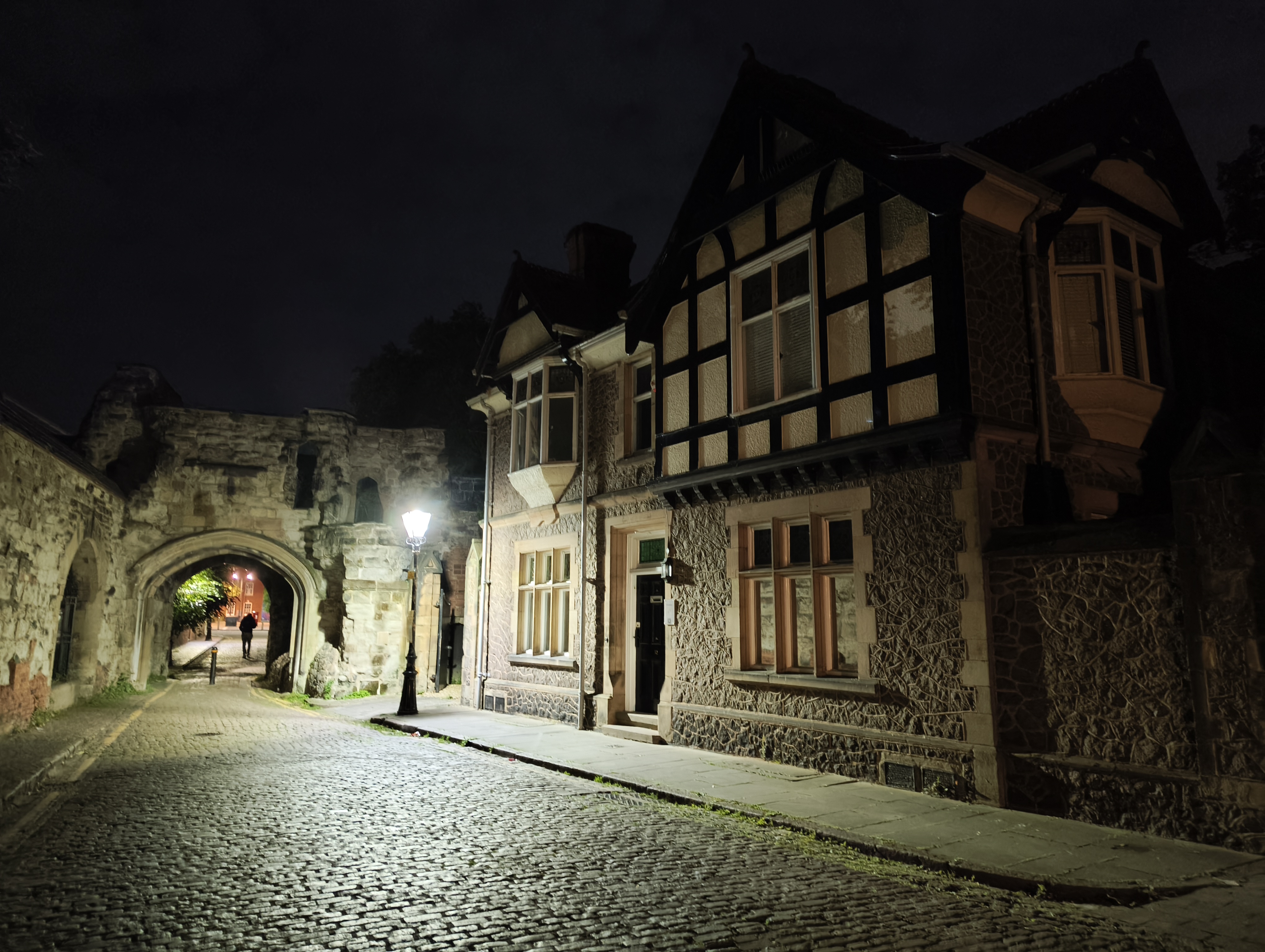 Cobbled Street in England with an old building let up at night by a street lamp