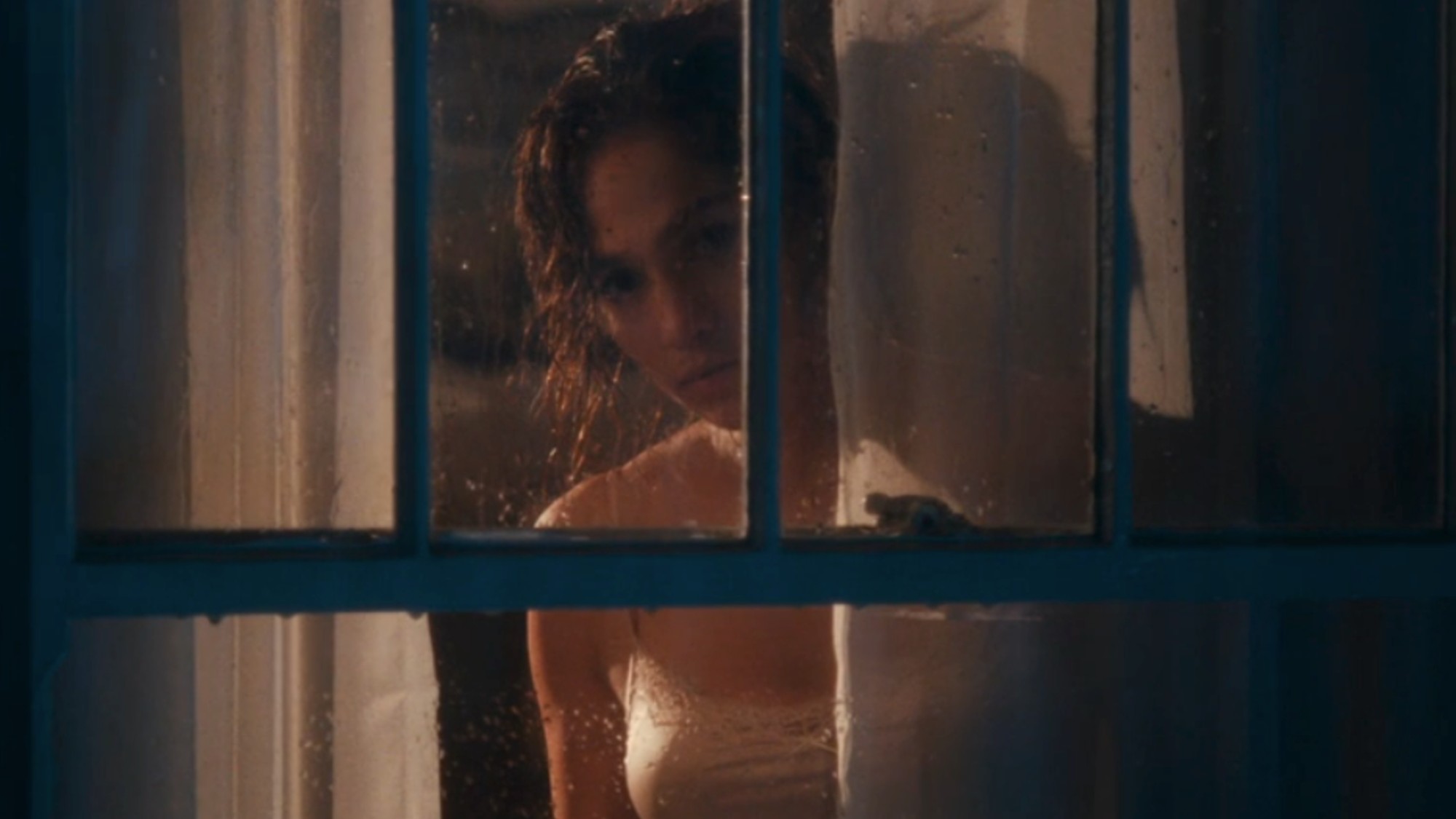 Jennifer Lopez looking out of a window at night in The Boy Next Door