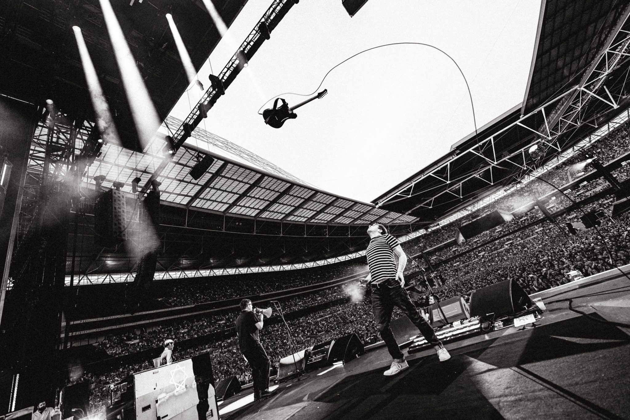 The band Blur performing on stage throwing a guitar in the air