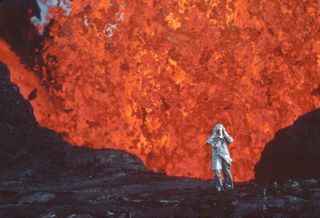 Katia Krafft wearing aluminized suit standing near lava burst at Krafla Volcano, Iceland in a scene from FIRE OF LOVE.