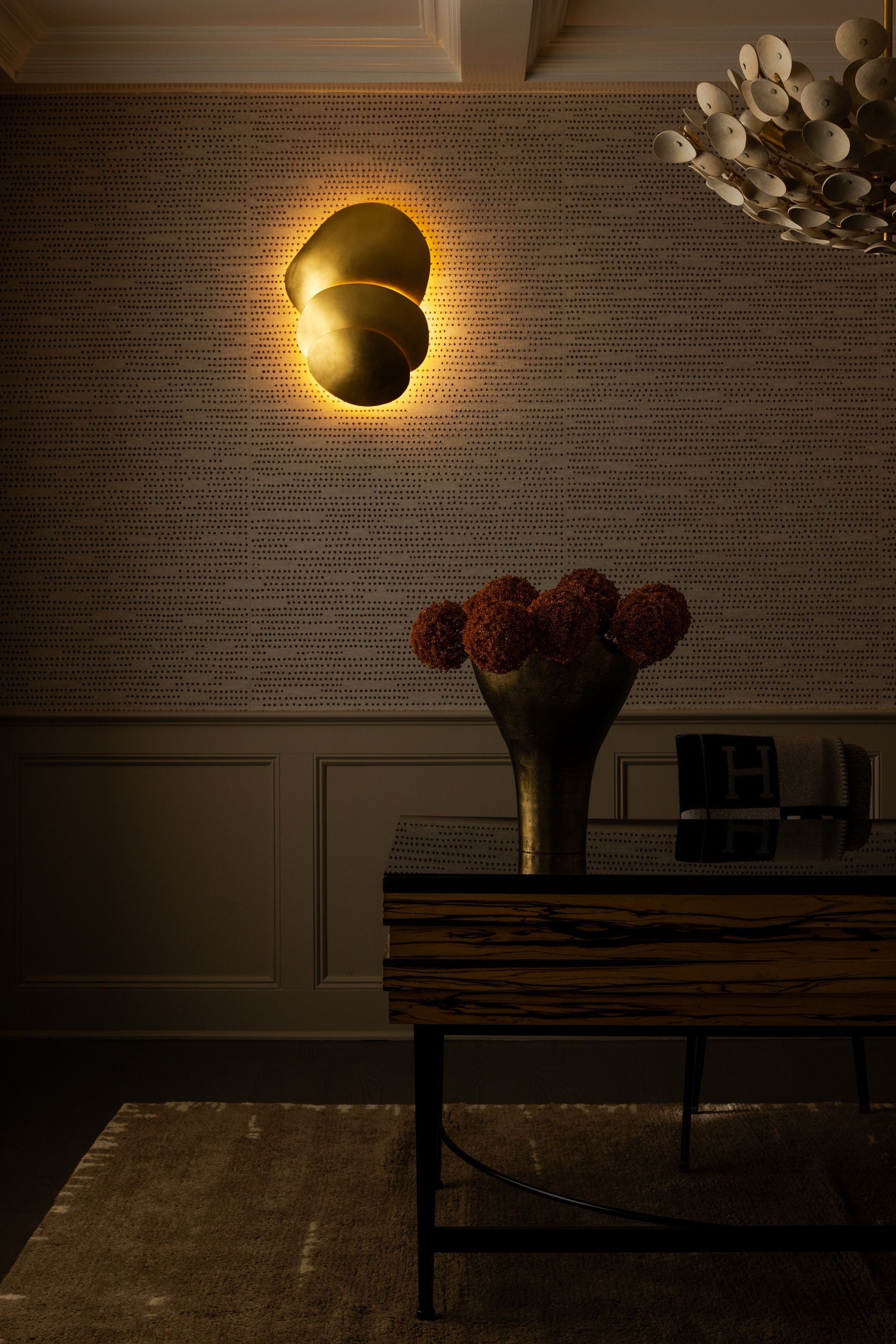 a home office with textured wallpaper, with a wall sconce turned on