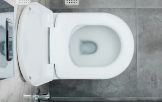 clean bright white toilet in an overhead shot, with a gray tile floor