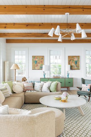 Exposed wooden beams, white walls and ceeling, sand colored sofa and green cabinet