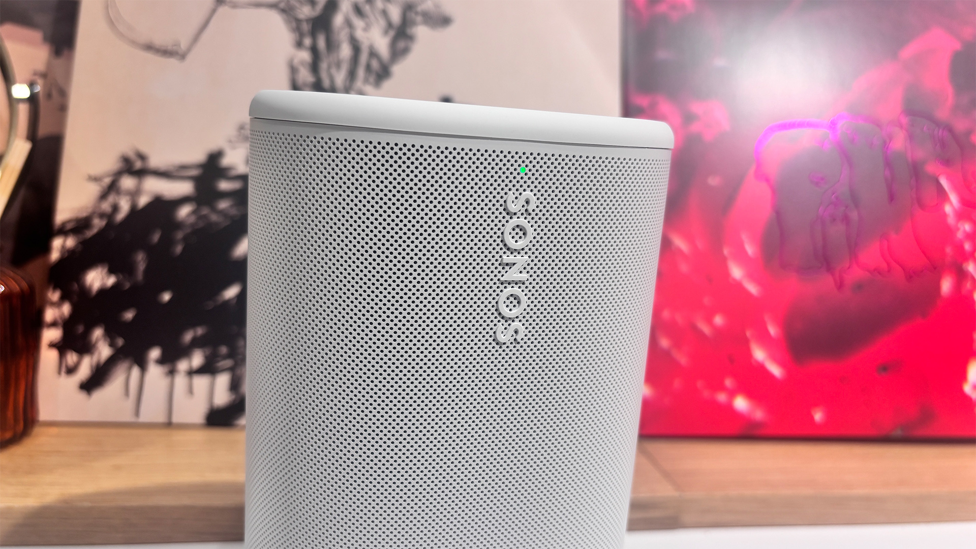 Sonos Play wireless speaker in white in front of busy bookcase