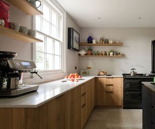 Oak kitchen cabinets topped with white countertops and a marble backsplash