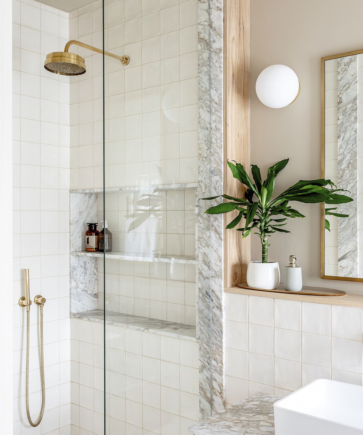 A new shower with brass fixtures and white times with a marble trim