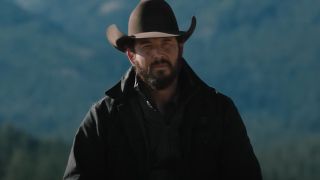 Cole Hauser as Rip in Yellowstone looking serious with mountains behind him. 