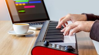 Person plays a small MIDI keyboard on a table